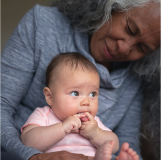 A grandmother holding her infant grandchild knowing her financial legacy is protected.