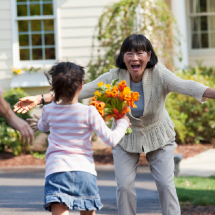 A grandmother greeting her young granddaughter with excitement, knowing she is protected with Protective Indexed Choice universal life insurance.