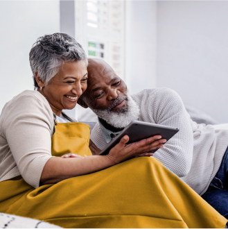 Smiling couple reading about the lifetime income options and how it can help safeguard their retirement income.
