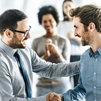 Two financial professionals shaking hands while an audience claps.