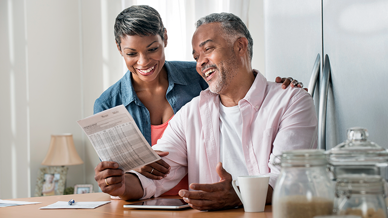 An affluent married couple smiling while reviewing details of their estate plan.