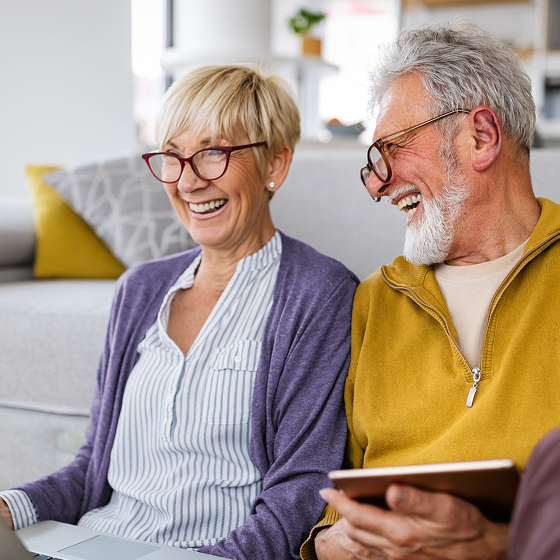 Video thumbnail of an older couple sitting on a couch and laughing together.