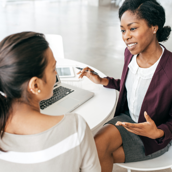  A financial professional talking to a client at a table, with a laptop.