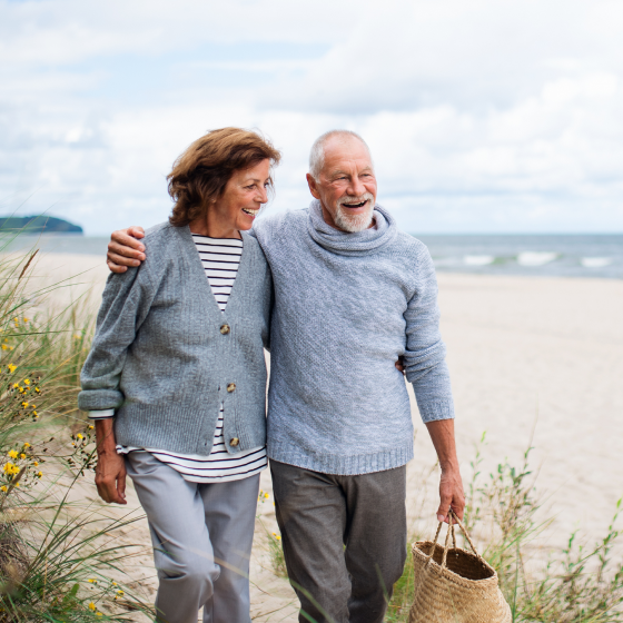 Image of pre-retirees, Tom and Lucy, walking on the beach.