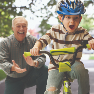 A grandfather teaching his grandson how to ride a bike.