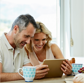 A couple smiling and using a tablet to review indexed universal life insurance.