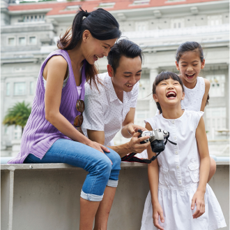 A family taking photos and smiling, knowing they are protected with term life insurance.