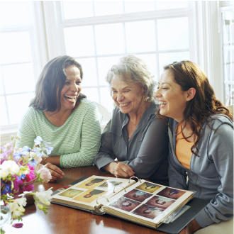 A woman and her adult daughters looking at a family photo album knowing they have an estate plan in place.