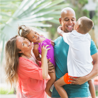 A mother and father playfully embrace their two children, feeling secure because they have life insurance.